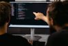 Two developers working on code, one man pointing at the screen.