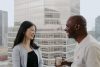 a young women and her man colleague drinking a coffee, chatting and smilling